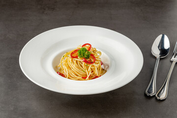 Spaghetti with paprika on white porcelain plate on dark stone table