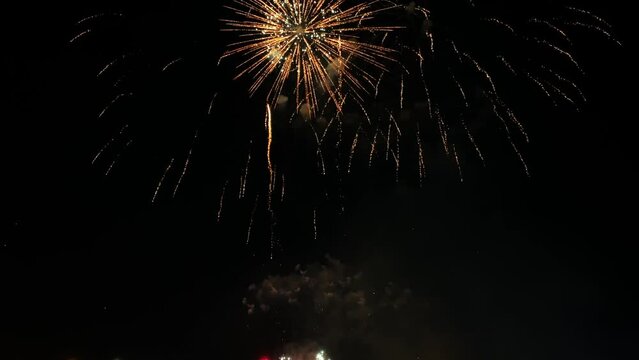 Multiple fireworks being set off and exploding in a bright and colorful display in the night time sky during national holiday, new year party or celebration event