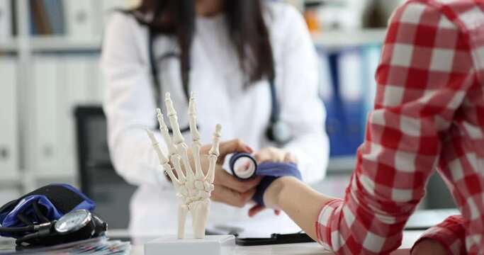 The doctor makes a bandaging of the wrist of a woman, close-up. Visit to the traumatologist, sprained tendon