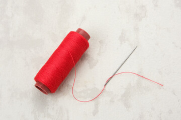 Red thread and needle on white table
