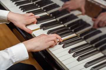Fototapeta premium The hands of a person who is learning to play the piano under the guidance of a teacher.