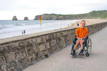 A disabled person in a wheelchair by the beach, having fun in summer