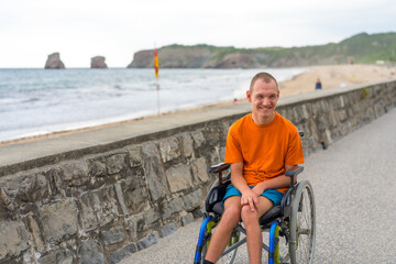 A disabled person in a wheelchair by the beach, having fun in summer