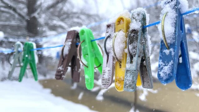 Multicolored Vintage clothespins on a rope in hoarfrost hang on a rope in the winter outside in the snow. Before Christmas. Snowing.