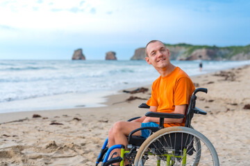 Portrait a disabled person in a wheelchair on the beach enjoying the freedom of the sea and nature