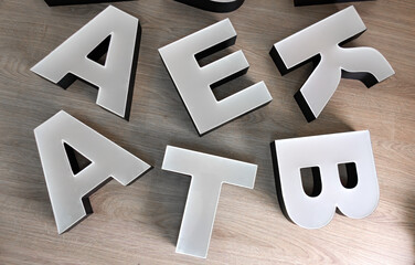 Plastic letters for the outdoor advertising logo on a wooden table.Production of advertising signs for the brand.