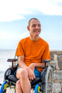 Portrait of pretty cheerful disabled person in wheelchair at the beach on summer vacation smiling