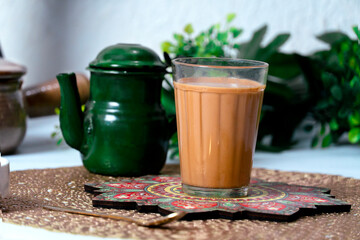 Fresh milk tea or indian karak chai in glass with chanak or masala tea in glass cup on textured background