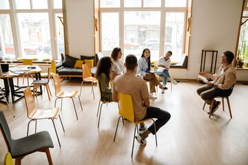 Group of students having discussion with lecturer while sitting in university library