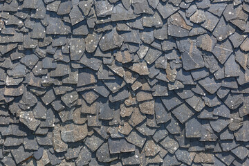 Detailed view of wall texture randomly lined with slate panels, typical and traditional shale stone material, used as external waterproof cladding in construction