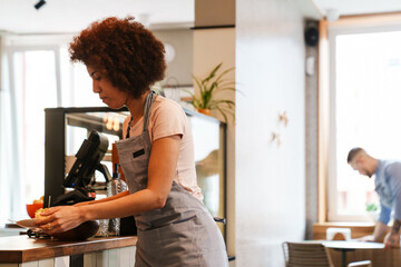 African waitress carrying plates with meal while working in cafe