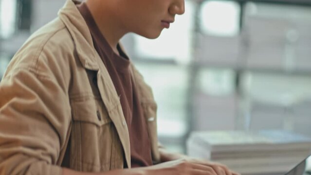Tilt down shot of male freshman using laptop to prepare for exam