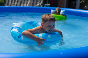 In summer, children swim in an inflatable pool with mugs and laugh. Children are enjoying the...