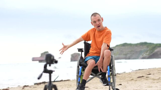 Portrait of a disabled person in a wheelchair on the beach recording a video