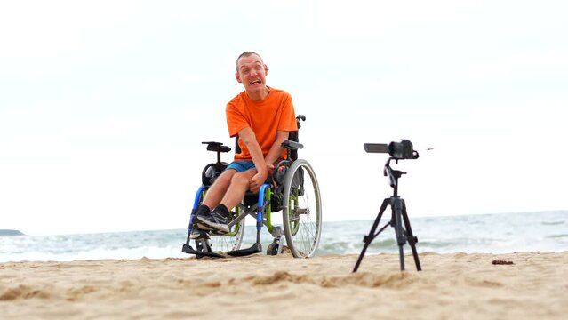 Portrait of a disabled person in a wheelchair on the beach recording a video blog