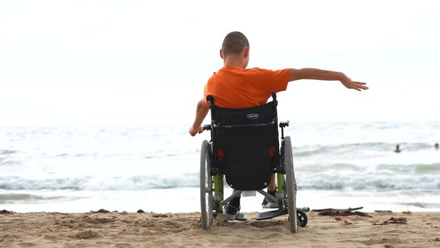 A disabled person on his back in a wheelchair on the beach feeling free by the sea