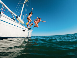 Happy friends diving from sailing boat into the sea - Travel and summer vacation concept - Soft...