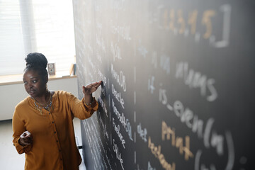 High angle view of African American teacher standing at blackboard at class