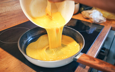 Scrambled eggs. Chef pouring liquid eggs on a hot pan. Making scrambled eggs.