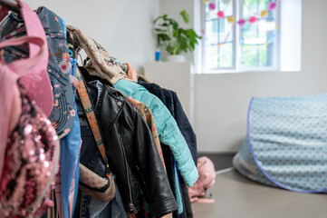 A lot of Children clothes hanging on rack in kindergarten room