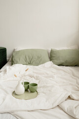 Close-up of a coffee cup on the bed with green pillows