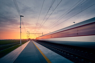 Railway at beautiful dawn. Long exposure of train on railroad track. Moving modern intercity passenger train..