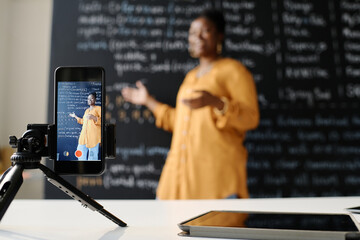 African American teacher using smartphone to teach students IT profession online