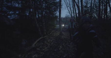 Group of kids run in forest at night, holding torch flash light, dolly out