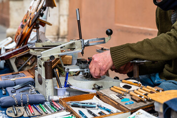 Elderly engraver at work on a street bench. Detail of the hands engrave plaques, pens and other objects. Old jobs.