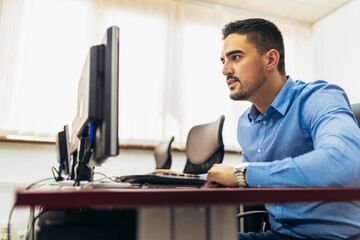 Young handsome businessman working hard on his computer in his office