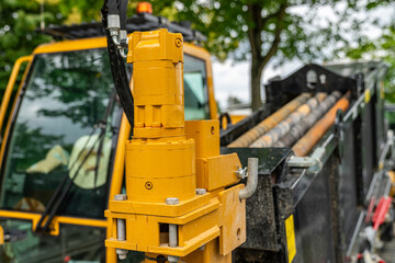 Close up of the yellow hydraulic part of the earth-moving machine.