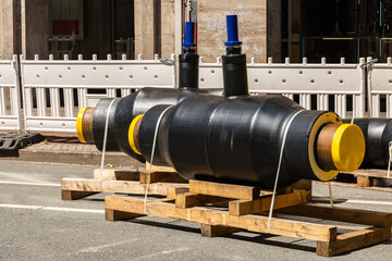 Short connecting insulated black pipes with yellow plugs on the side of a city street.