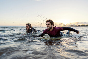 Surfers swimming towards waves in the ocean. - obrazy, fototapety, plakaty