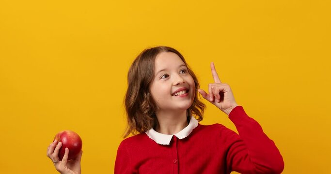 Stylish smiling school teenage girl hits an apple on the head
