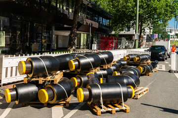 A lot of short connecting insulated black pipes with yellow plugs on the side of a city street.