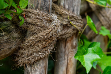 Old shaggy rope tied around a wooden pole. Close up.