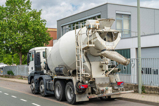 A large car with a concrete mixer stands on the side of the city road.