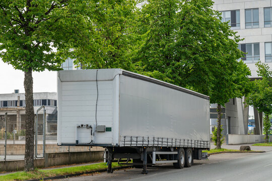 Large semi-trailer parked on the side of the city road.