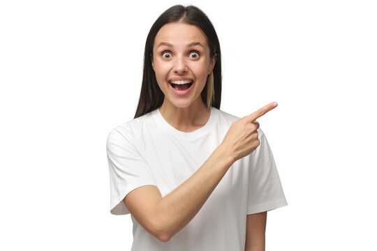 Young surprised woman in white t-shirt pointing right with her finger, shouting WOW