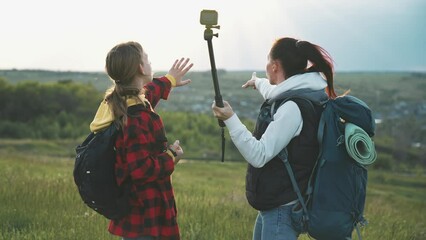 Mom and daughter in nature shoot video blog on camera a selfie stick about tourist trip on mountain. Family walk in outdoor at weekend. Healthy lifestyle. Happy girls at good emotions smile and laugh