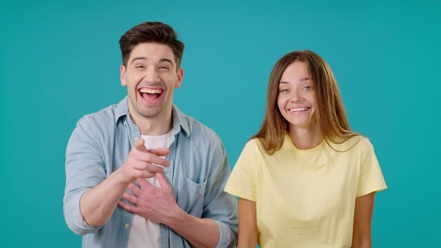 Young man and woman laugh pointing fingers and mocking
