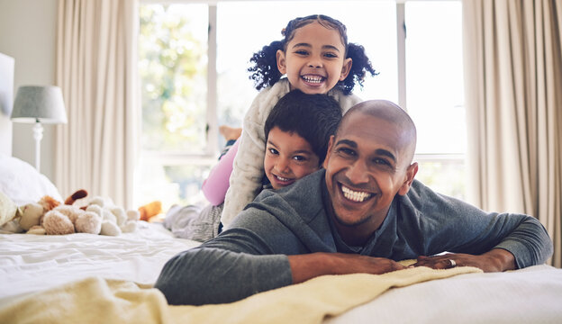 Bed, playful and portrait of a father with children for love, care or bonding in the morning. Happy, family and a young dad with kids in the bedroom of a house for quality time and playing together