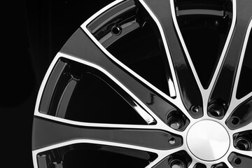 Close-up of an aluminum cast wheel from a car with black spokes on a black background