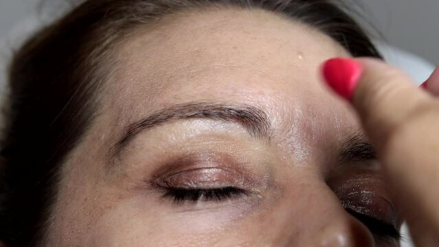 The beautician depilates a woman's eyebrows with the ancient Arab thread technique. Manual technique popular in many Arab and Asian countries.