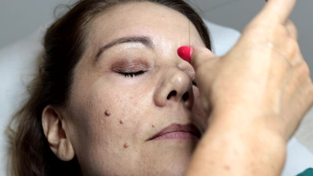 The beautician depilates a woman's eyebrows with the ancient Arab thread technique. Manual technique popular in many Arab and Asian countries.