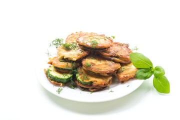 zucchini fried in circles in batter with herbs, in a plate.