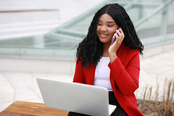 Fototapeta premium beautiful african female with laptop is calling by phone