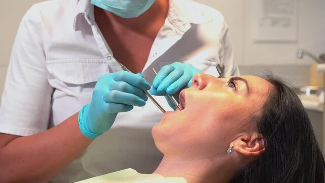 Dentist examining oral cavity mouth of the patient in dental chair with mirror and tools in medical office. Hygiene and health of oral teeth