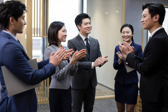 Cheerful Chinese business people applauding in office