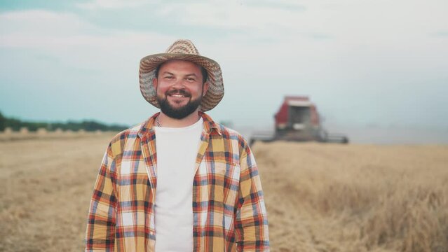 Farmer man in hat walks through wheat field and touches ripe wheat ears with his hands, controlling and checking quality. Summer harvest season. Agronomist specialist is engaged in growing plants.